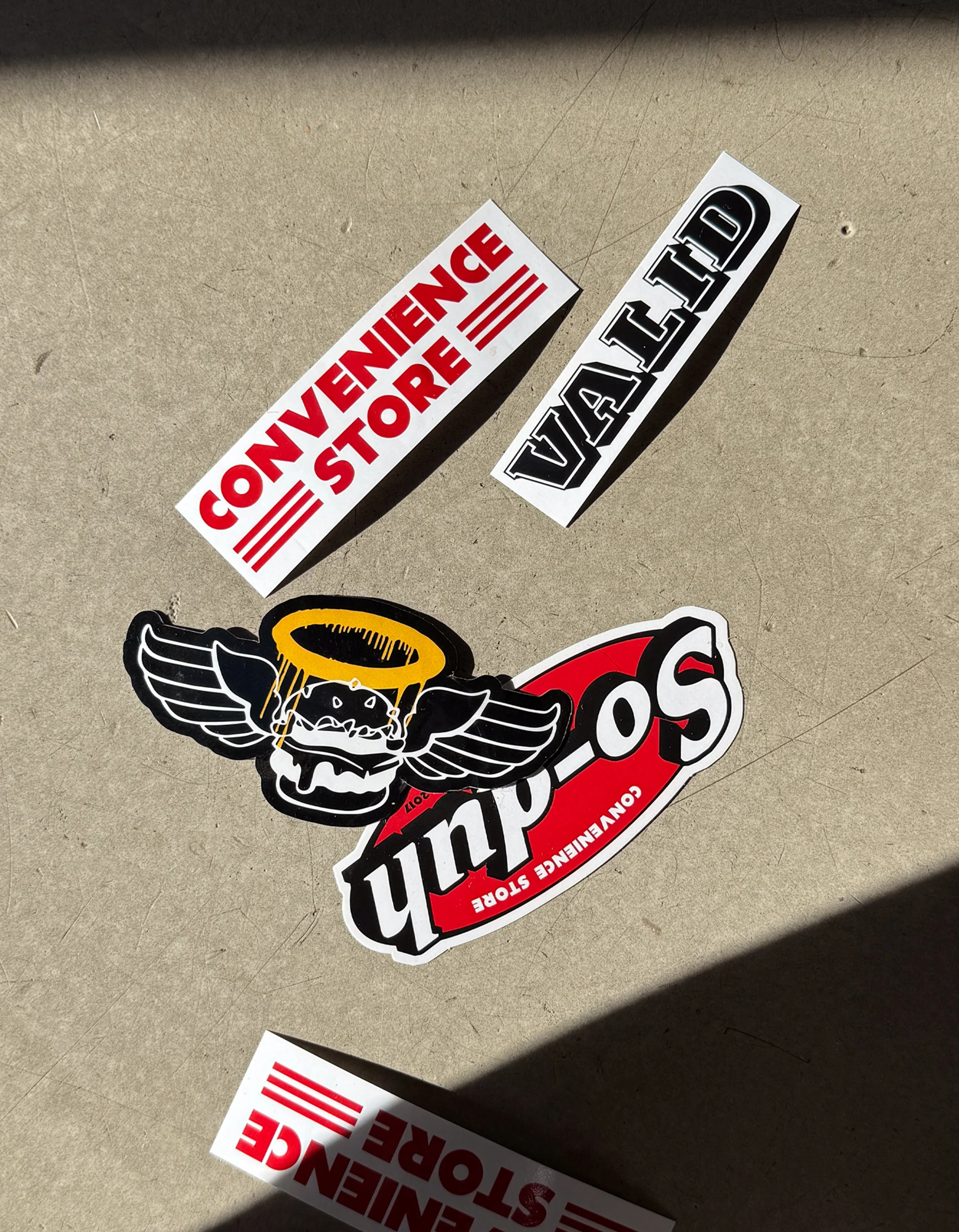 Almost Famous die-cut stickers including a winged burger logo laid out on kraft paper