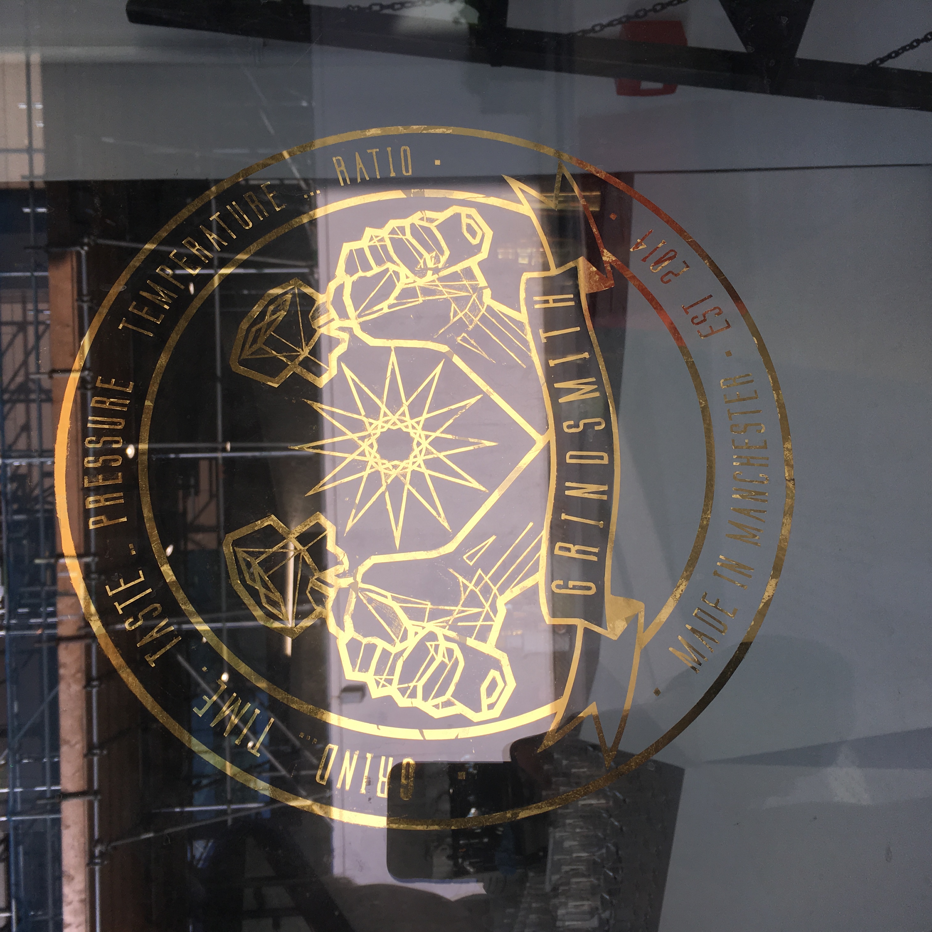 Grindsmith gold-leaf vinyl crest applied to a coffee shop window, made in Manchester