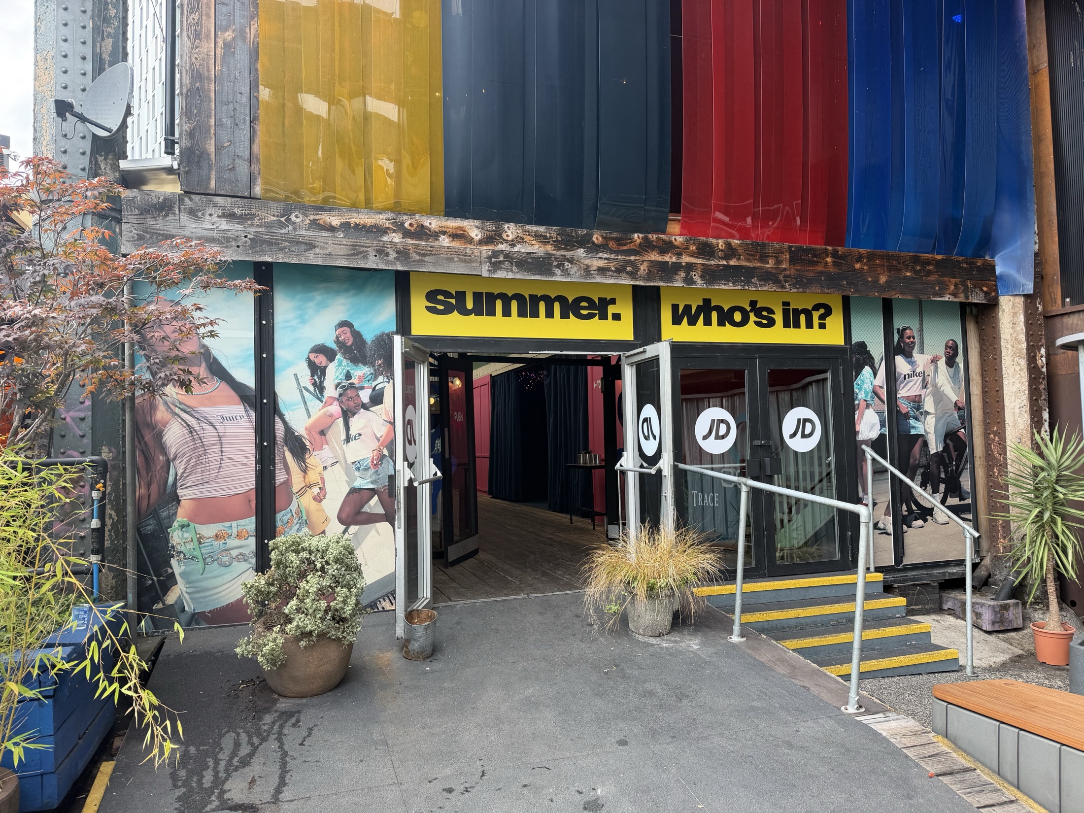 JD Sports 'summer, who's in?' activation at Freight Island, Manchester, with printed shipping-container banners, window graphics and JD signage above the entrance